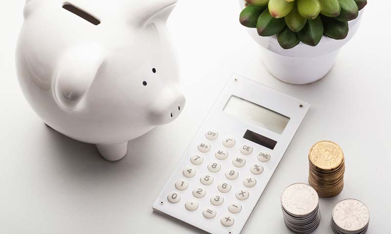 a calculator, piggy bank, and coins on a table