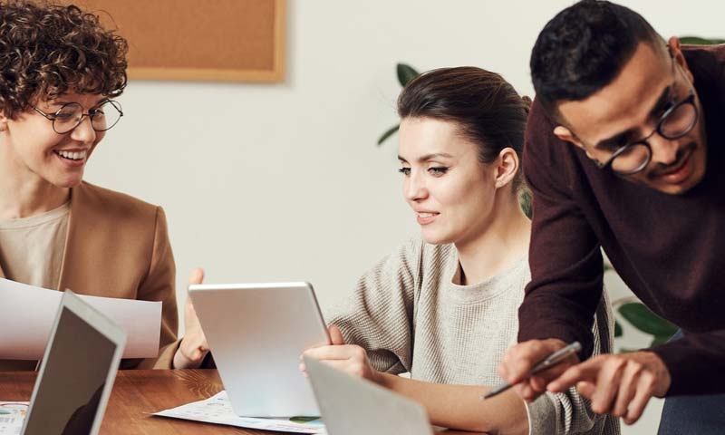 legal-entity Business people gathered around a table with papers and laptops interacting with eachother.