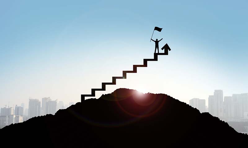 steps-to-success silhouette of a business person climbing steps and raising arms in celebration.