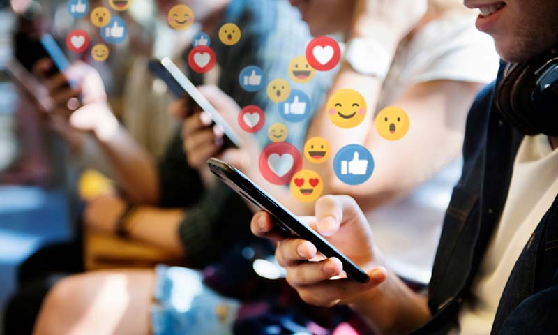 likes-to-loves People using social media apps on their phones with likes, loves, and smiles icons rising from the screens.