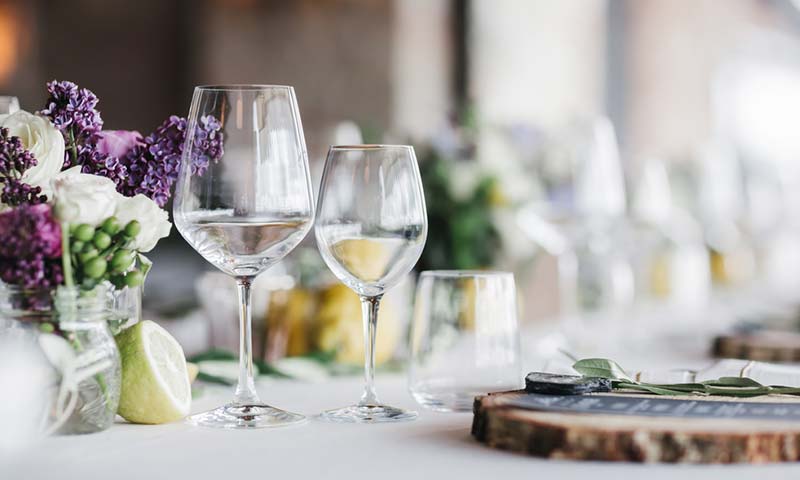 A classy table place setting with flowers and wine glasses