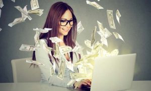 A woman using a laptop while dollar bills are flying out of the screen.
