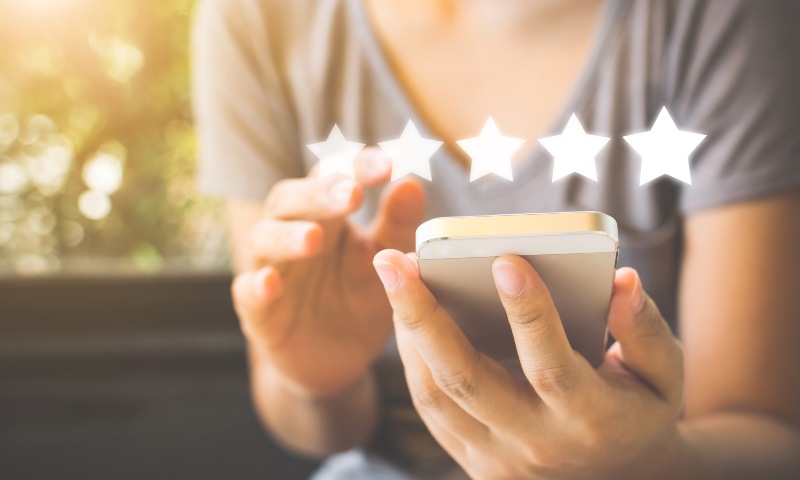 close up of a lady on her phone, five white stars above the phone suggesting she is rating something