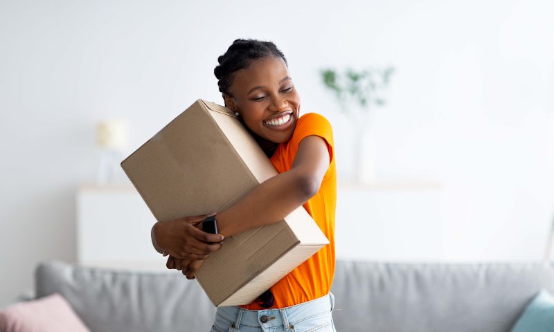 Woman hugging a package tightly, huge smile on her face