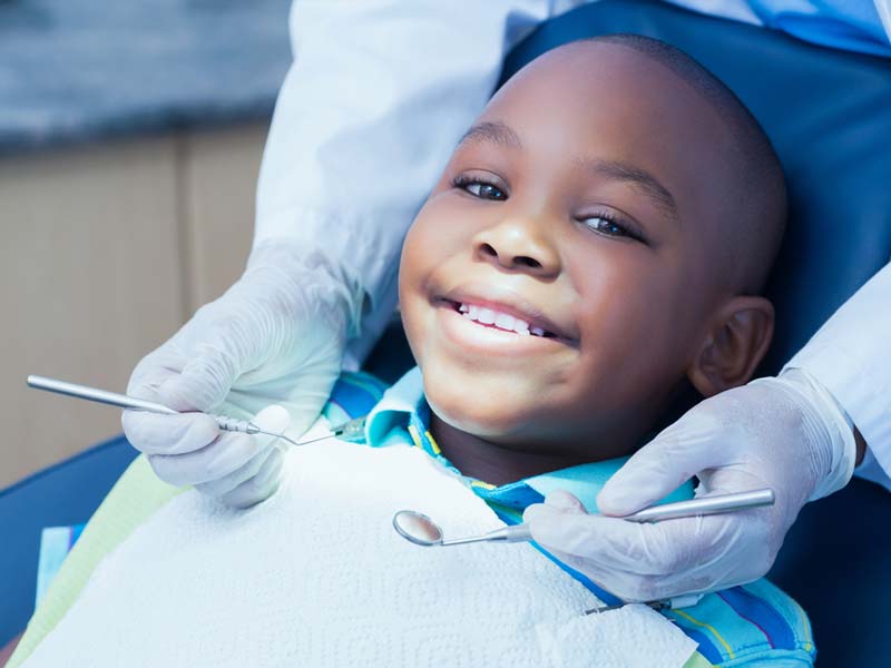 A young boy smiling while sitting in the dentist chair