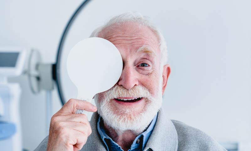 Smiling senior man covering one eye at a vision exam
