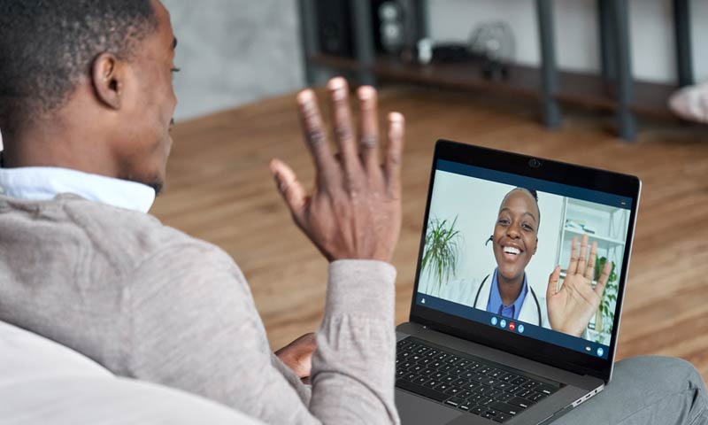 Man waiving at his doctor on a laptop video call