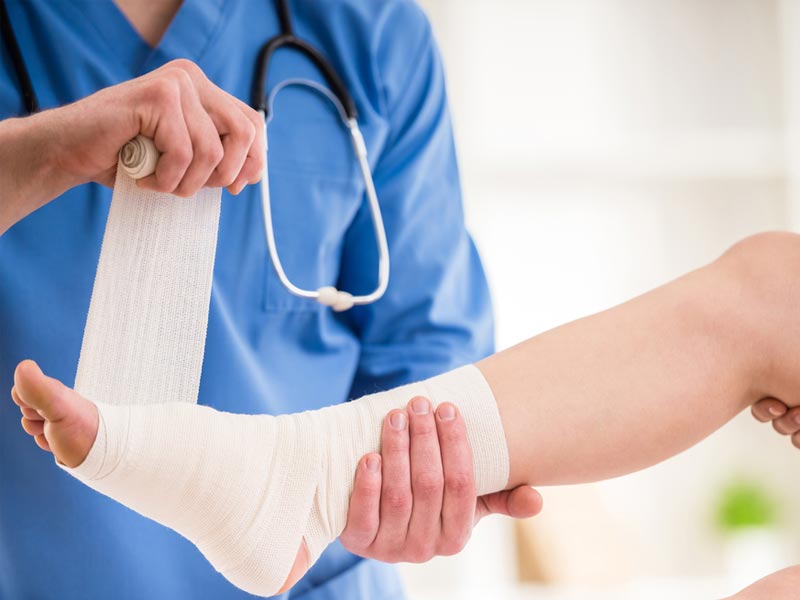 Medical professional wrapping a sprained ankle