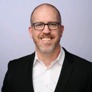 Jason Alexander, man with shaved head, glasses, black sport coat