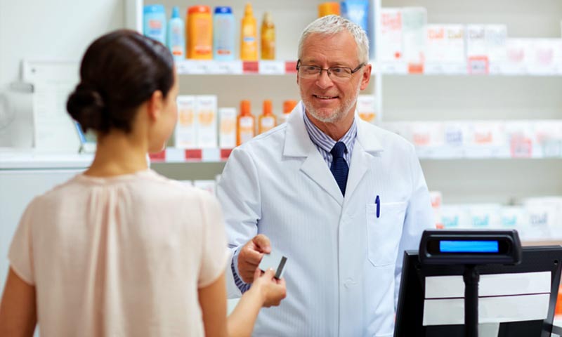 A customer handing her card to the pharmacist