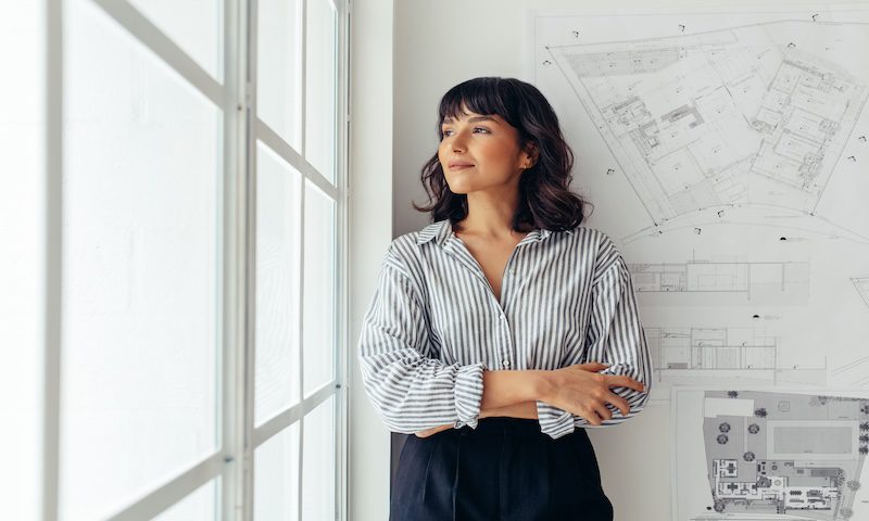 Woman standing near architectural drawings in a bright office